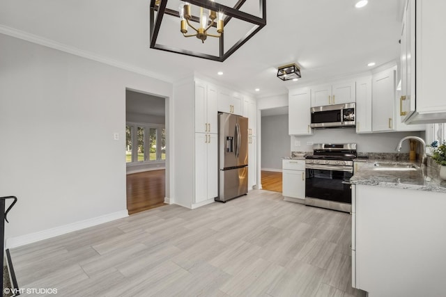 kitchen featuring sink, crown molding, appliances with stainless steel finishes, light stone countertops, and white cabinets