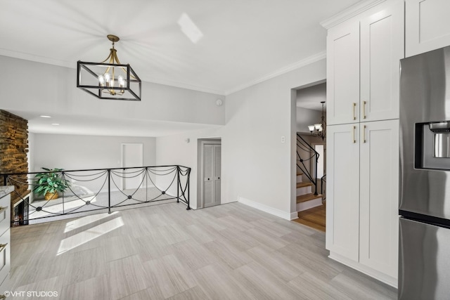 unfurnished living room featuring an inviting chandelier, ornamental molding, and light hardwood / wood-style flooring