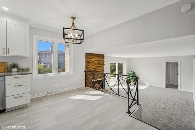 unfurnished dining area with a notable chandelier, crown molding, and a fireplace