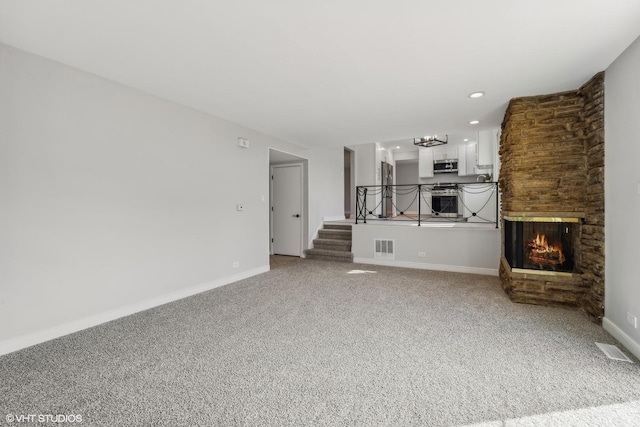 unfurnished living room featuring carpet flooring and a multi sided fireplace