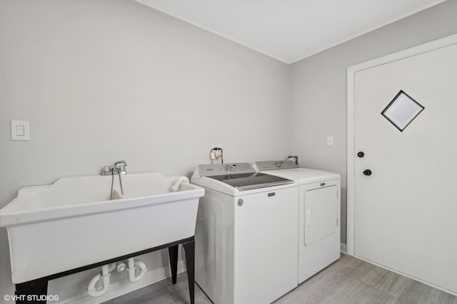 washroom featuring sink, washer and dryer, and light wood-type flooring