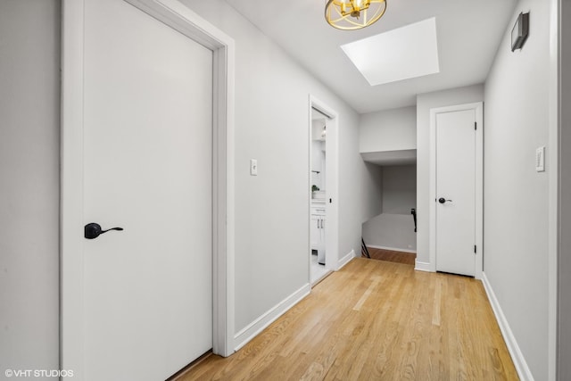 laundry area featuring a skylight and light hardwood / wood-style flooring