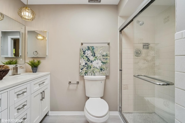 bathroom with vanity, a shower with door, and toilet