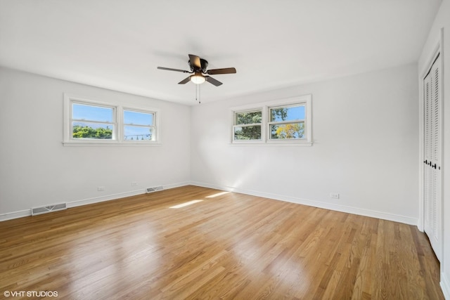 unfurnished bedroom with ceiling fan, a closet, multiple windows, and light wood-type flooring