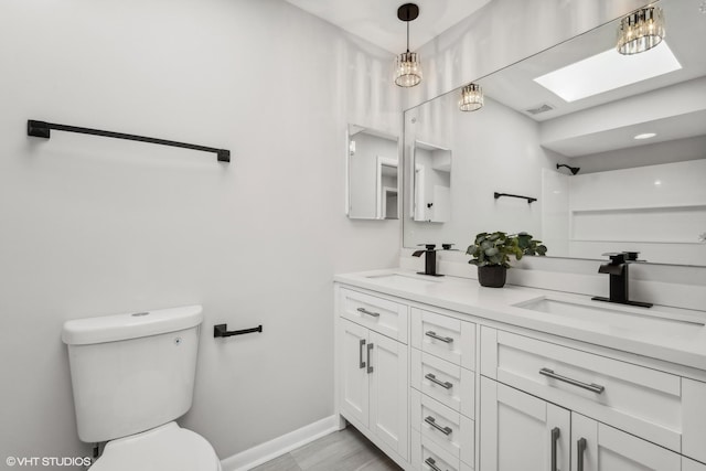 bathroom featuring vanity, a skylight, and toilet