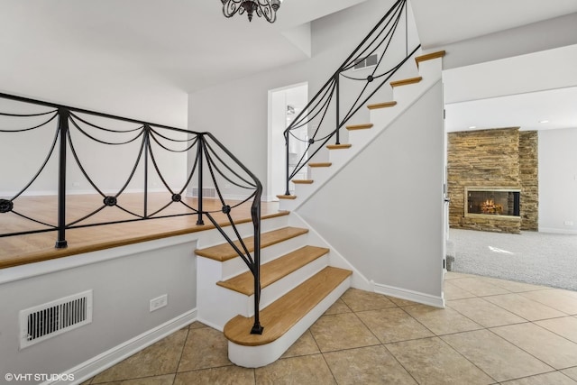 stairs featuring a stone fireplace and tile patterned floors