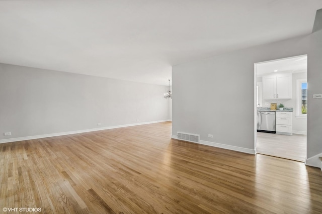 unfurnished living room with light hardwood / wood-style flooring and a notable chandelier