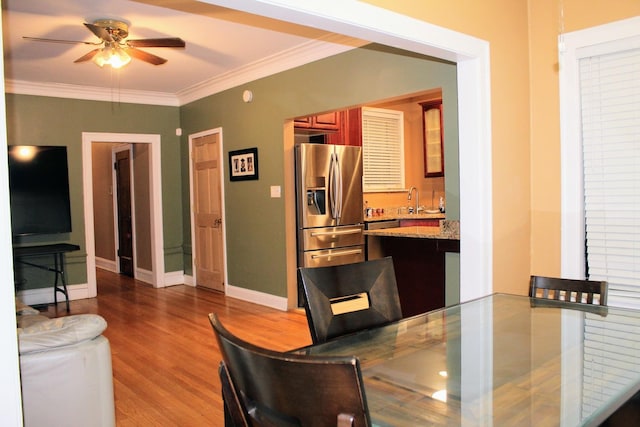 dining area featuring ornamental molding, wood-type flooring, wet bar, and ceiling fan