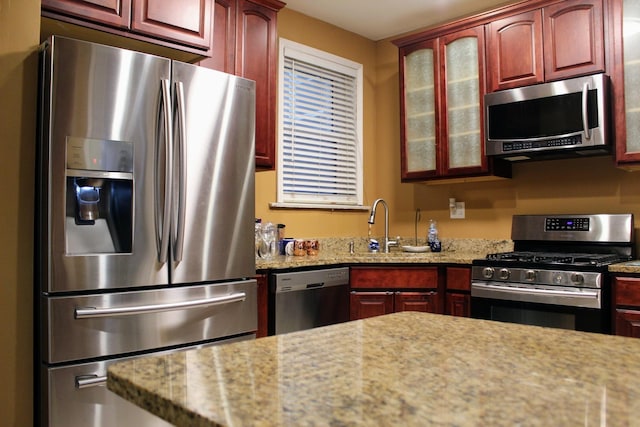 kitchen with light stone counters, stainless steel appliances, and sink