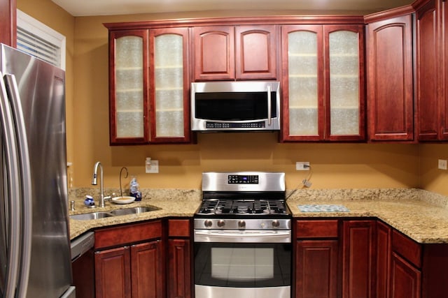 kitchen featuring light stone countertops, appliances with stainless steel finishes, and sink