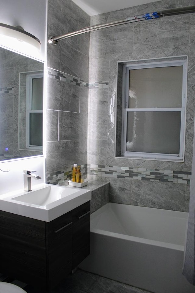 bathroom featuring vanity, tile walls, and tiled shower / bath