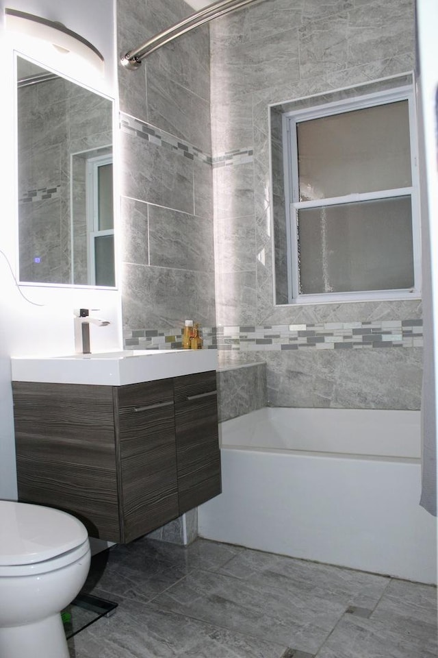 full bathroom with tiled shower / bath combo, vanity, tile walls, and toilet