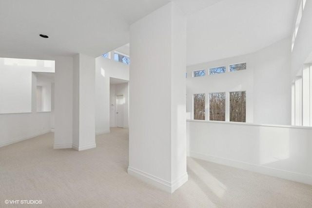 interior space with light colored carpet and a towering ceiling