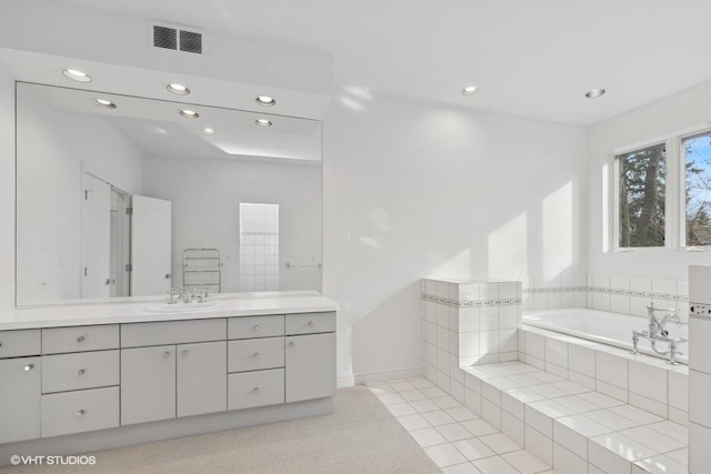 bathroom with vanity, tile patterned floors, and tiled bath