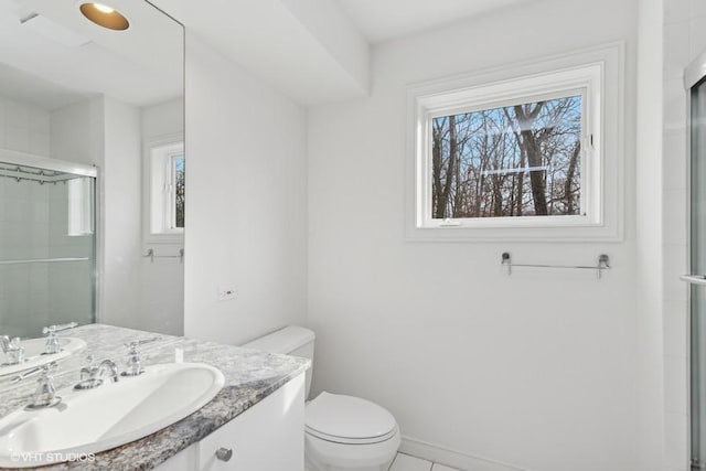 bathroom featuring vanity, a shower with shower door, and toilet