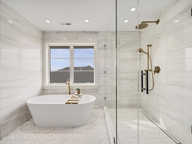 bathroom featuring visible vents, tile walls, a shower stall, and a soaking tub