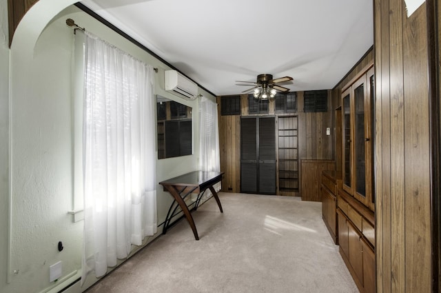 interior space with ceiling fan, light colored carpet, wooden walls, and an AC wall unit