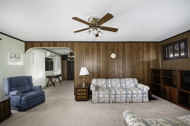 living room with wood walls, a wall mounted AC, ornamental molding, carpet flooring, and ceiling fan