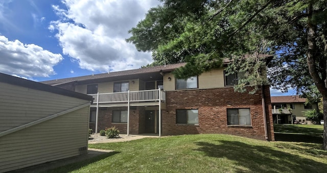 rear view of house featuring a balcony and a lawn