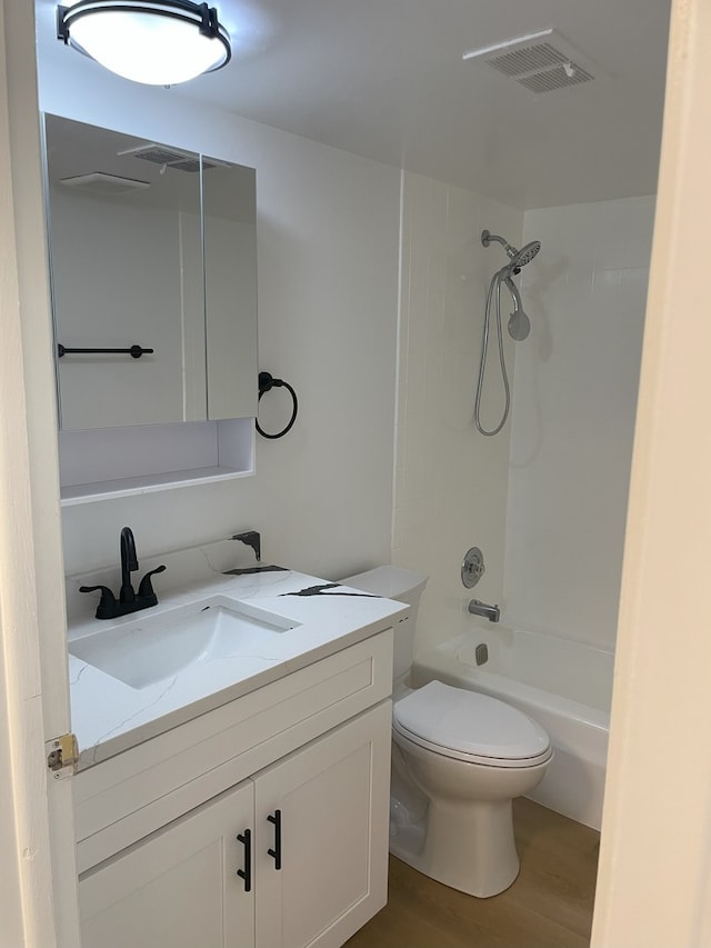 full bathroom featuring hardwood / wood-style flooring, vanity, tiled shower / bath combo, and toilet