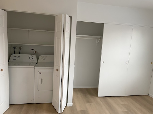 clothes washing area with washing machine and clothes dryer and light hardwood / wood-style floors