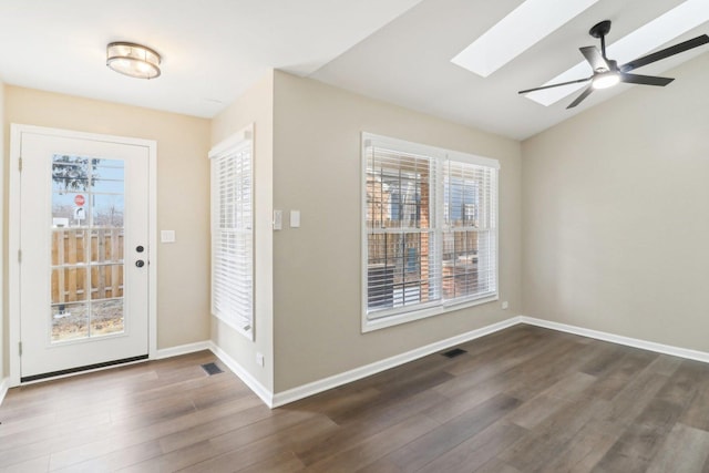 entrance foyer featuring dark hardwood / wood-style flooring, a wealth of natural light, lofted ceiling with skylight, and ceiling fan