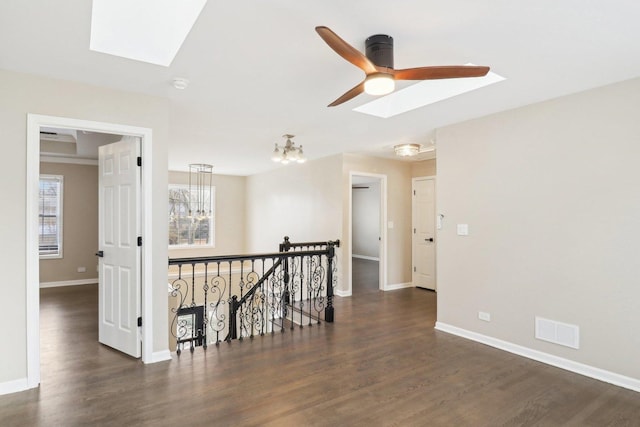 unfurnished room with dark wood-type flooring, plenty of natural light, and a skylight