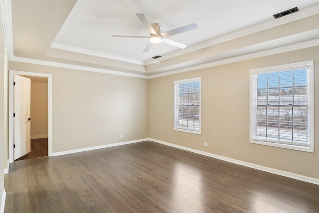 empty room featuring crown molding, dark wood-type flooring, a raised ceiling, and ceiling fan