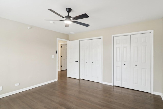 unfurnished bedroom with multiple closets, ceiling fan, and dark hardwood / wood-style flooring