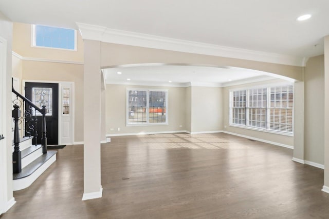 unfurnished living room with crown molding, dark wood-type flooring, and a wealth of natural light