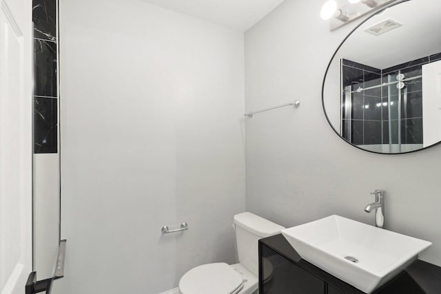 bathroom with tiled shower, vanity, and toilet