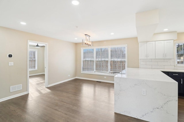 kitchen with pendant lighting, dark wood-type flooring, white cabinetry, backsplash, and light stone countertops