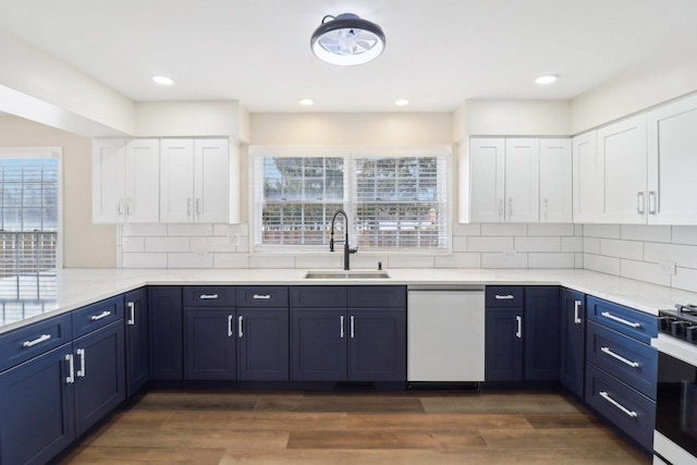 kitchen featuring white dishwasher, sink, white cabinetry, and blue cabinets