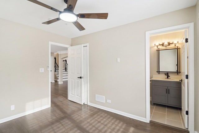 unfurnished bedroom with ensuite bathroom, dark wood-type flooring, sink, and ceiling fan