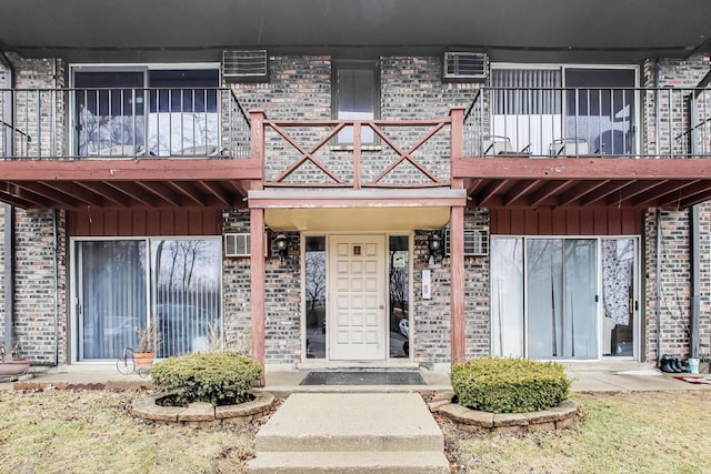 view of exterior entry featuring a wall mounted air conditioner and a balcony