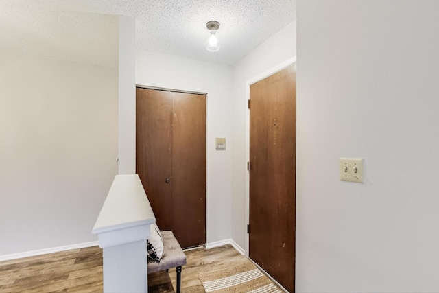 hall with a textured ceiling and light hardwood / wood-style flooring