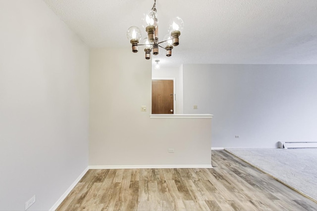 unfurnished dining area featuring an inviting chandelier, hardwood / wood-style flooring, a baseboard radiator, and a textured ceiling