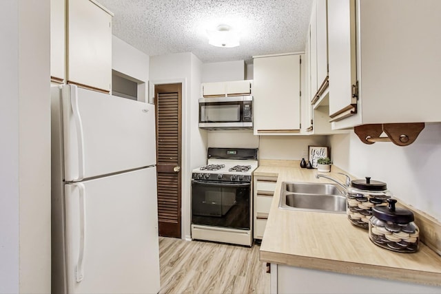 kitchen featuring sink, white appliances, light hardwood / wood-style flooring, white cabinetry, and a textured ceiling