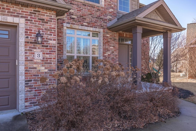 view of exterior entry featuring brick siding and an attached garage