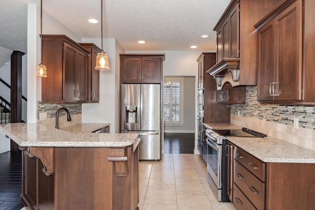 kitchen featuring a peninsula, appliances with stainless steel finishes, light stone counters, and pendant lighting