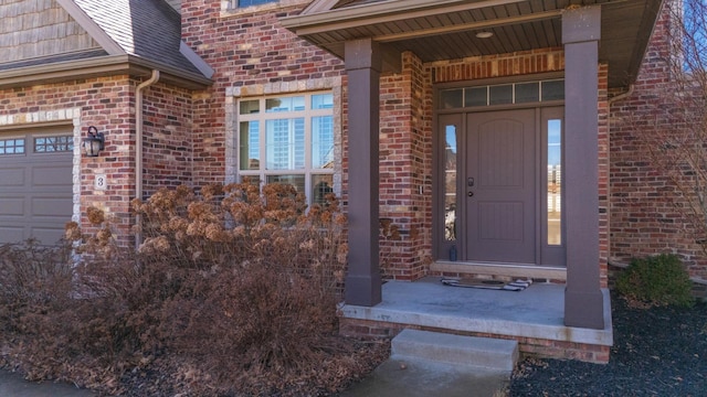 entrance to property featuring a garage and brick siding