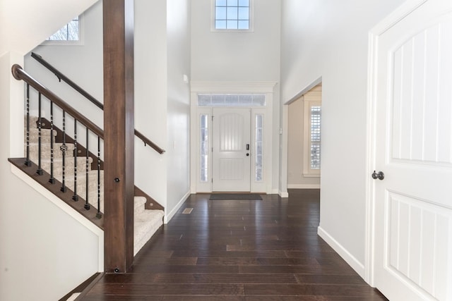 foyer featuring stairs, a towering ceiling, baseboards, and wood finished floors