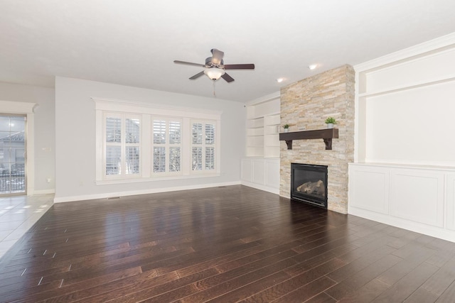 unfurnished living room featuring built in features, a ceiling fan, a fireplace, and dark wood-style floors