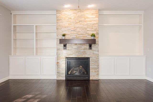 unfurnished living room featuring baseboards, dark wood-style flooring, and a stone fireplace