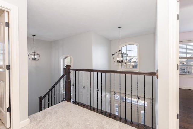 hallway featuring a chandelier, baseboards, and an upstairs landing