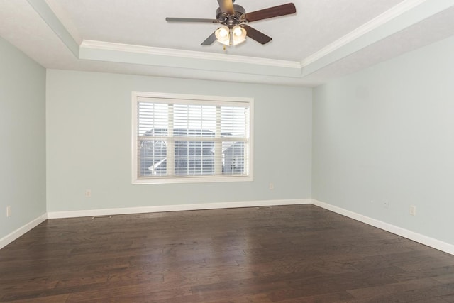 unfurnished room with ornamental molding, a raised ceiling, and dark wood finished floors