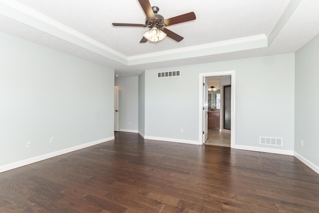 empty room featuring visible vents, a tray ceiling, and wood finished floors