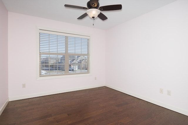 empty room featuring dark wood-style flooring, a ceiling fan, and baseboards