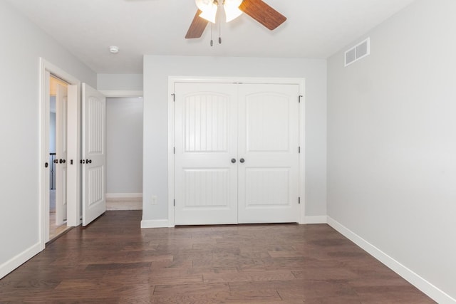 unfurnished bedroom featuring ceiling fan, dark wood-type flooring, visible vents, baseboards, and a closet