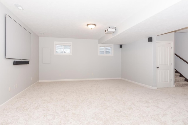 carpeted empty room with stairway and baseboards